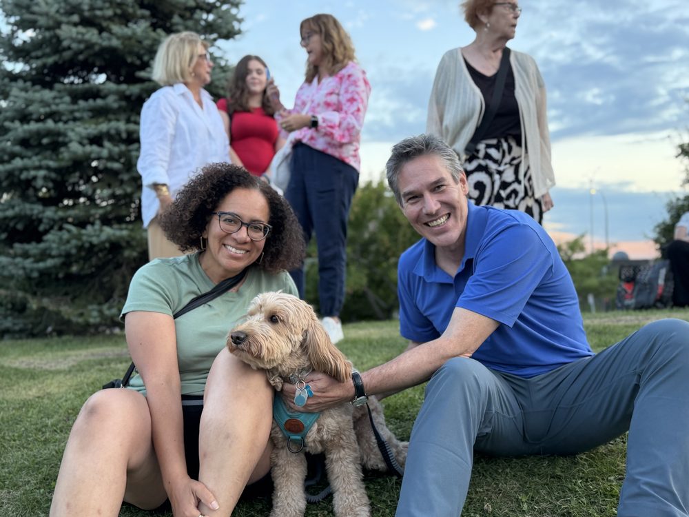 Nicolas Plourde assis dans l'herbe avec une citoyenne et son chien